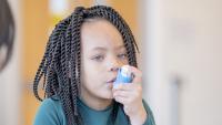 Pulmonologist showing child how to use inhaler.